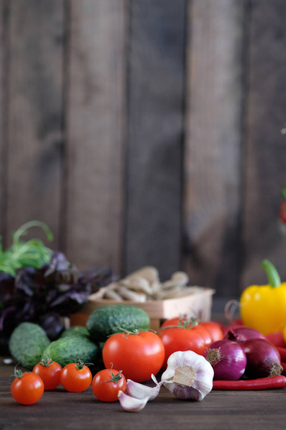 Vegetable.Fresh vegetables: tomatos, cucumbers,peppers,mushrooms,radishes, garlic ,onions and green seasonings on  old rustic oak table. - Фото, изображение