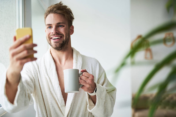 Smiling man making selfie in hotel in morning - Foto, afbeelding