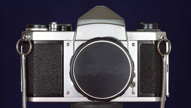 Primer plano de una cámara analógica vintage plateada y negra con fondo azul
 - Foto, imagen