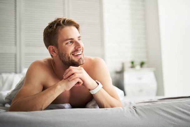 Cheerful man enjoying new day in bed - Foto, imagen
