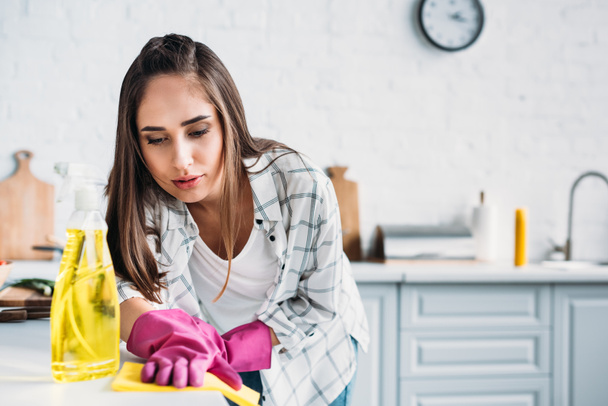 girl cleaning kitchen counter with rag at home - Valokuva, kuva