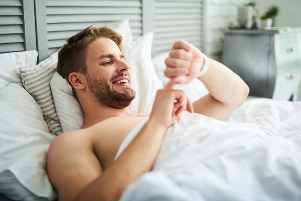 Young joyful man lying in bed  - Foto, imagen