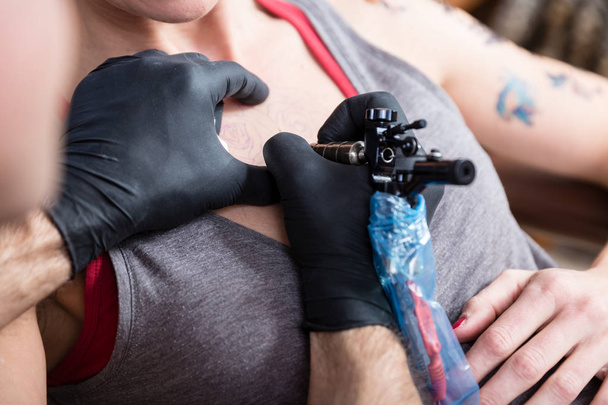 Close-up das mãos de um tatuador tatuando duas rosas
 - Foto, Imagem