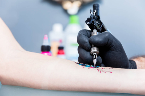 Γκρο πλαν του χεριού του ένα τατουάζ καλλιτέχνη σκίαση μια πολύχρωμη πεταλούδα - Φωτογραφία, εικόνα