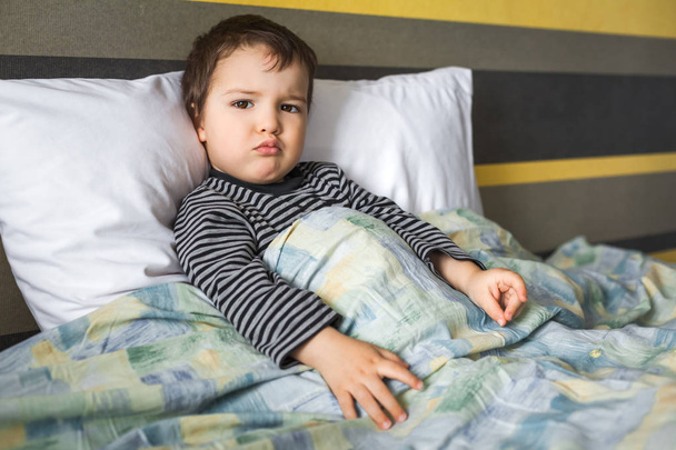 disappointed ill boy toddler sitting on bed - Foto, imagen