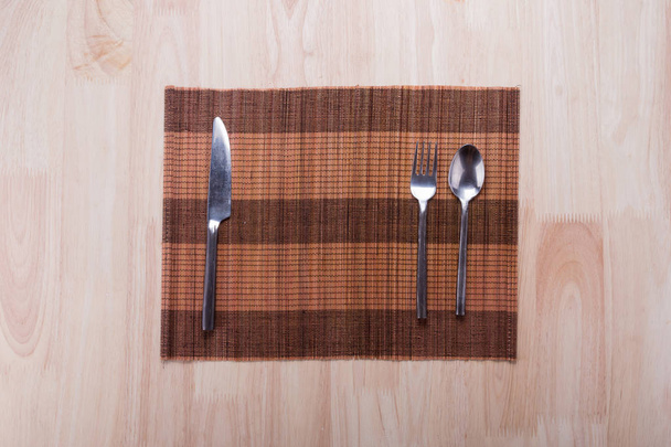 Top view of knife, spoon and fork with napkin on wooden table - Valokuva, kuva