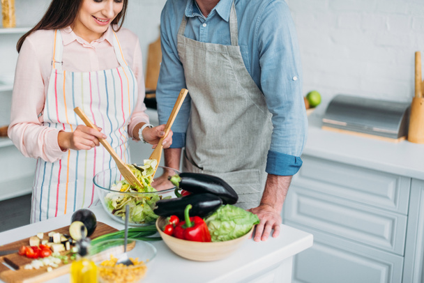 abgeschnittenes Bild der Freundin beim Kochen und Mischen von Salat in der Küche - Foto, Bild