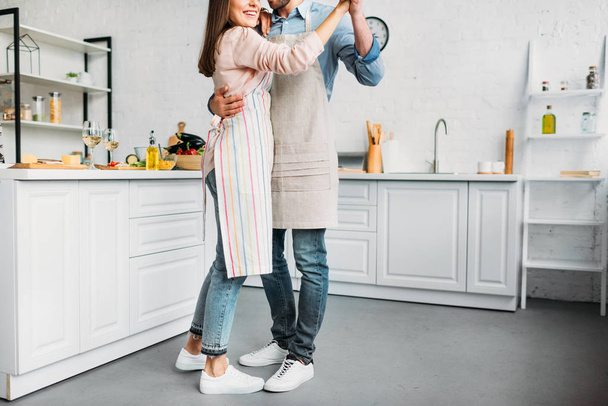 обрезанный образ пары, обнимающей и танцующей на кухне
 - Фото, изображение