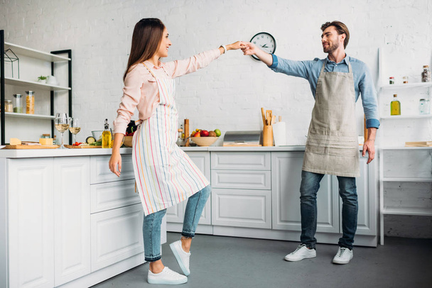 couple holding hands and dancing in kitchen - Foto, imagen