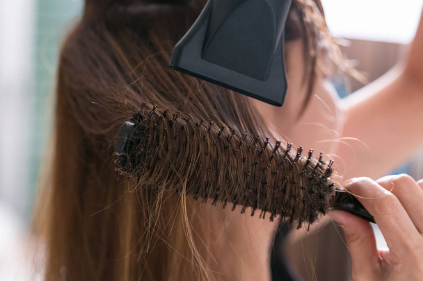 Drying blond hair with hair dryer and round brush. - Photo, Image
