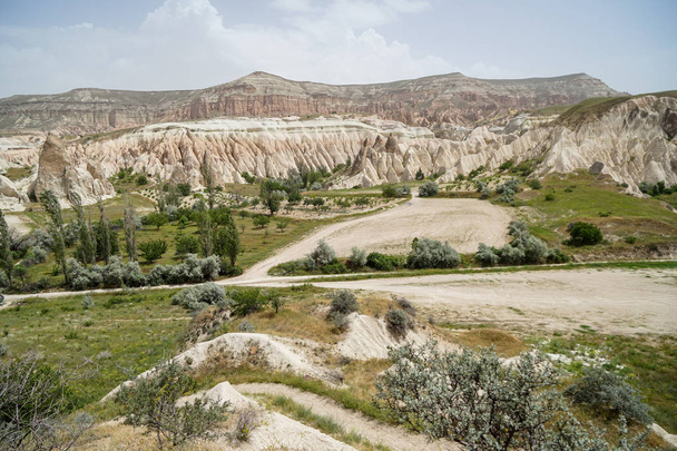 Malownicza panorama pejzaż widok doliny czerwonego i różowego Wyświetlono ostry kamień górski i zielonej pustynnej rośliny z tło nieba, Kapadocja, Turcja - Zdjęcie, obraz
