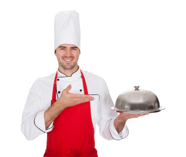 Portrait of cheerful chef presenting silver tray - Фото, изображение