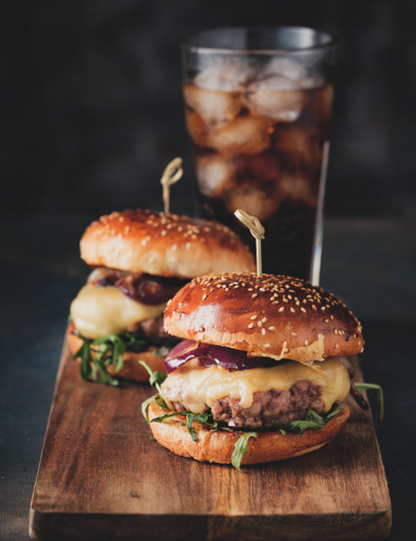 Street food, fast food. Homemade juicy burgers with beef, cheese and caramelized onions on the wooden table. Toned image. - Photo, Image