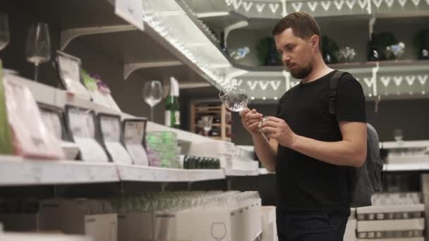 ein junger Mann wählt schöne Brillen im Einkaufszentrum für seine neue Wohnung - Filmmaterial, Video