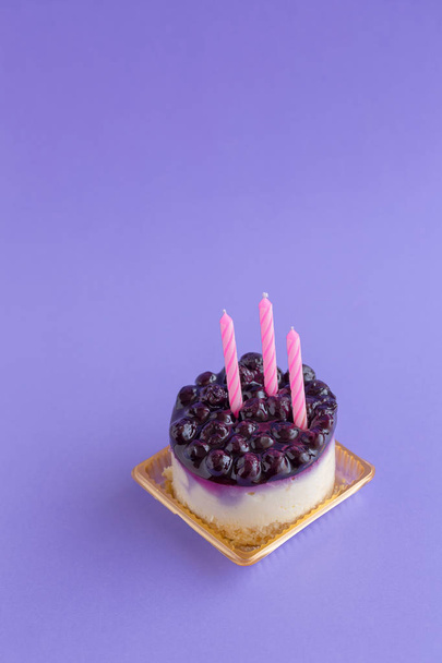 Cheesecake de mirtilo com velas no fundo violeta
. - Foto, Imagem