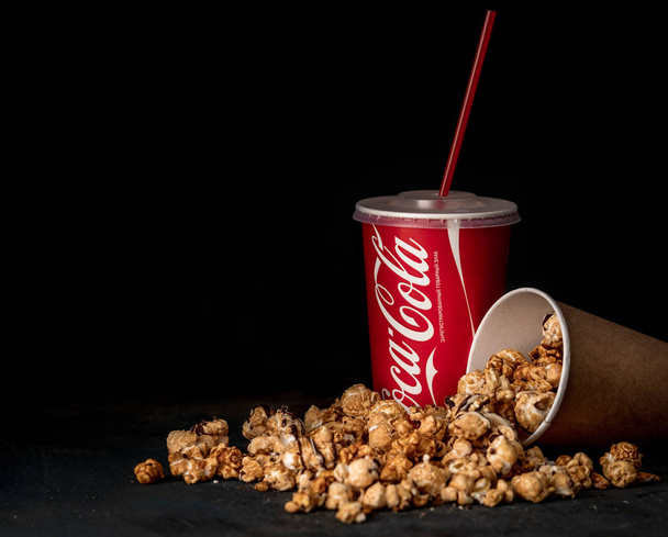 MINSK, BELARUS, APRIL 4, 2018: Cup of Coca Cola with popcorn on a dark background - Photo, Image