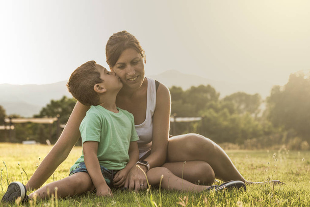 Małego chłopca całować jego matka na polu w lecie - Zdjęcie, obraz