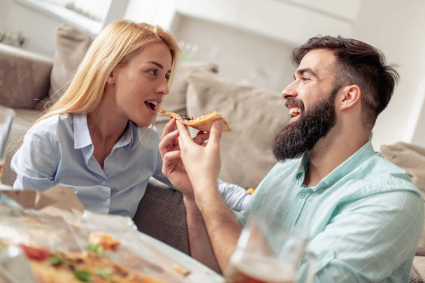 Ζευγάρι τρώει πίτσα σνακ στο σπίτι. - Φωτογραφία, εικόνα