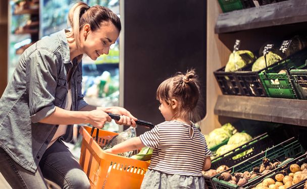 Moeder en dochter zijn winkelen bij de supermarkt, het concept van familierelaties en gezond eten - Foto, afbeelding