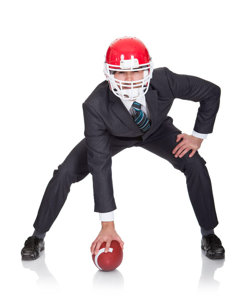 Competitive businessman playing american football - Foto, afbeelding