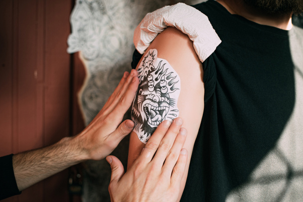 recortado tiro de tatuaje artista transferir boceto de tatuaje en el hombro en salón de tatuaje
  - Foto, Imagen