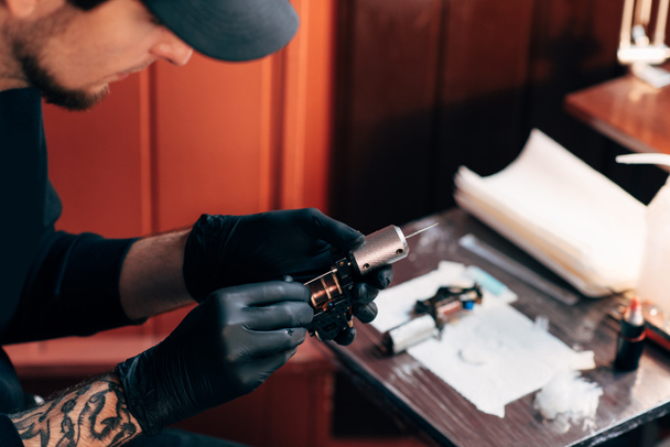 selective focus of tattoo artist in gloves with tattooing machine in salon - Photo, Image