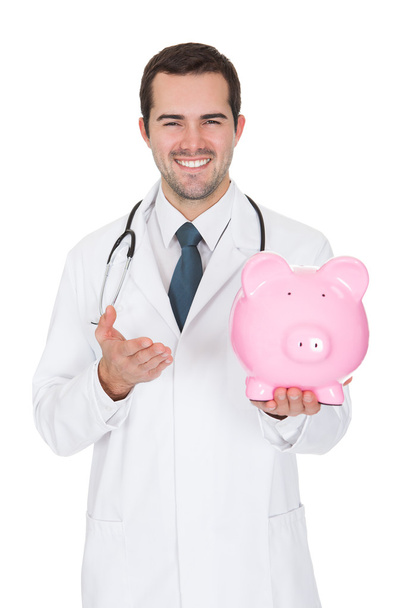 Young Female Doctor Holding Piggy Bank - Photo, image