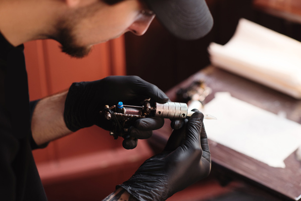 szelektív összpontosít a tetoválás művész, kesztyű, tetoválás szalon gép - Fotó, kép