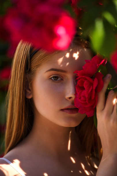 portrait of young redhead woman posing in flowers - Fotoğraf, Görsel