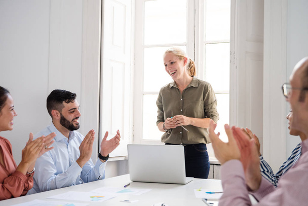 Vrouw erkennen lof en applaus van een groep gemotiveerde collega's in een office-omgeving na een oeuvre - Foto, afbeelding
