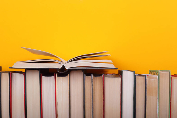 Wetenschap en onderwijs - Open boek op een horizontale stapel groep van colorfull boeken over de houten tafel en gele achtergrond. - Foto, afbeelding