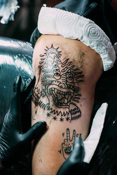 részleges kilátás tattoo művész tattoo vállon szalonban dolgozik kesztyű - Fotó, kép
