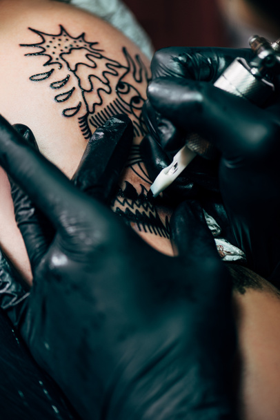 bijgesneden shot van het tatoeëren proces op schouder in salon - Foto, afbeelding