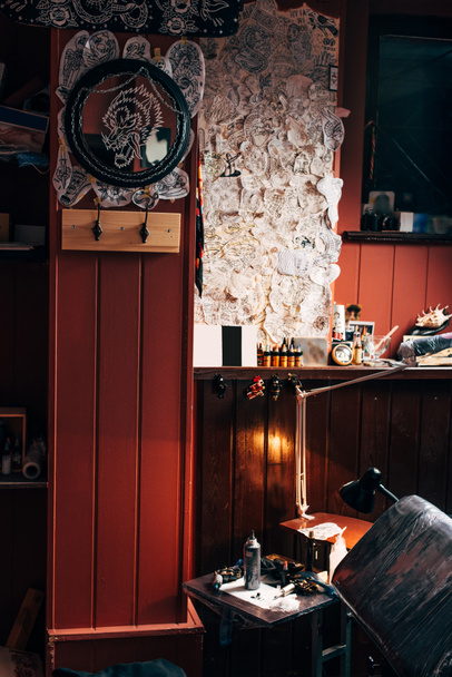 vista de cerca de bocetos en la pared, máquinas de tatuaje arregladas y pintura en el salón de tatuajes
 - Foto, Imagen