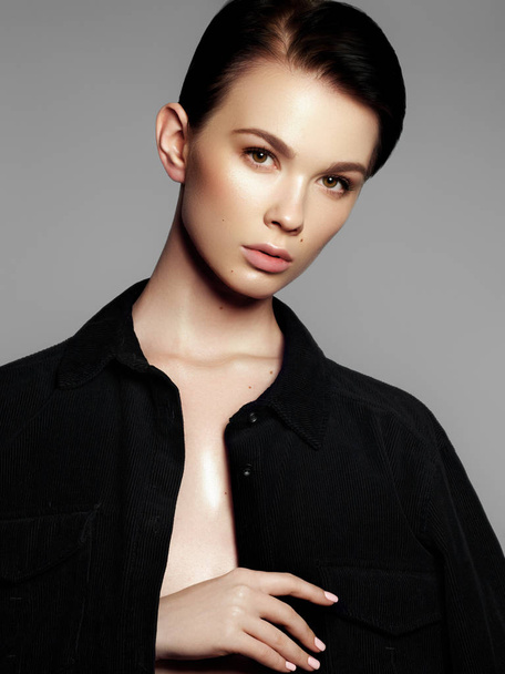 Portret van een fotomodel in een zwart shirt. Mooie jonge vrouw op een grijze achtergrond. Model met natuurlijke make-up. Mode make-up - Foto, afbeelding