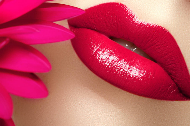 Salón de belleza y spa. Primer plano de unos hermosos labios rojos sexys. Bonitos labios llenos con maquillaje de labios rosados. Maquillaje de moda. Labios sexy. Parte de la cara de la mujer con la piel limpia
 - Foto, Imagen