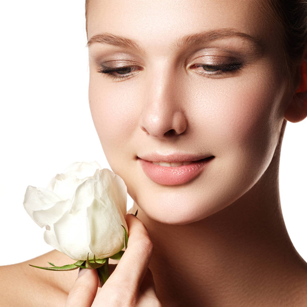 Pretty face of beautiful young woman with rose on hands - white background. Beauty face of young woman with flower. Beauty treatment concept - Φωτογραφία, εικόνα