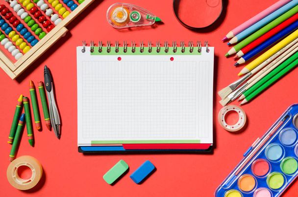 Notepad and school supplies, office stationery, red background. Blank notepad for your text. - Foto, imagen