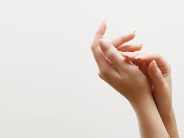 De zorg van de huid van de hand. Close-up van de mooie vrouw handen met lichte manicure op nagels. Crème voor handen en behandeling. - Foto, afbeelding