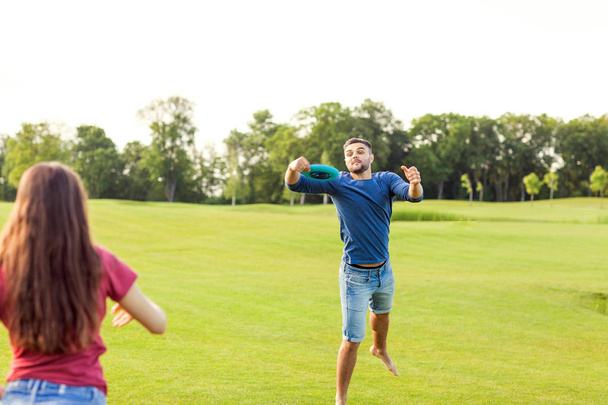 paar verliefd spelen frisbee in het park, het concept van een gezonde levensstijl. - Foto, afbeelding
