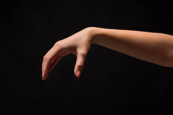 Vrouwelijke hand oppakken van iets, knipsel op zwart - Foto, afbeelding