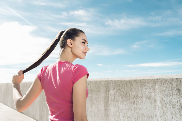 confiante delgado menina de cabelos longos em uma camiseta rosa descansando e ganhando força antes de treinar ao ar livre
 - Foto, Imagem