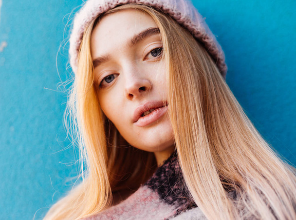 beautiful stylish blonde girl in hat posing against blue wall background - Zdjęcie, obraz