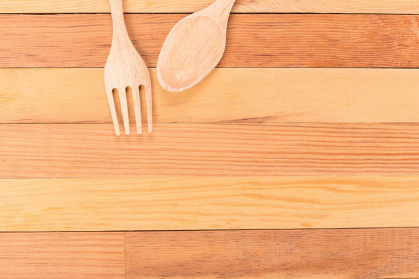 Vista dall'alto di forchetta in legno e cucchiaio su sfondo in legno chiaro
 - Foto, immagini