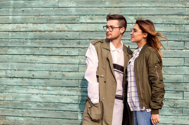 fashion couple standing posing near green wooden wall - Foto, imagen