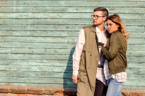 pareja de moda de pie posando cerca de pared de madera verde
 - Foto, Imagen