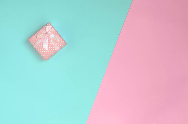 Petite boîte cadeau rose se trouvent sur fond de texture de papier de couleurs bleu pastel et rose mode dans un concept minimal
. - Photo, image
