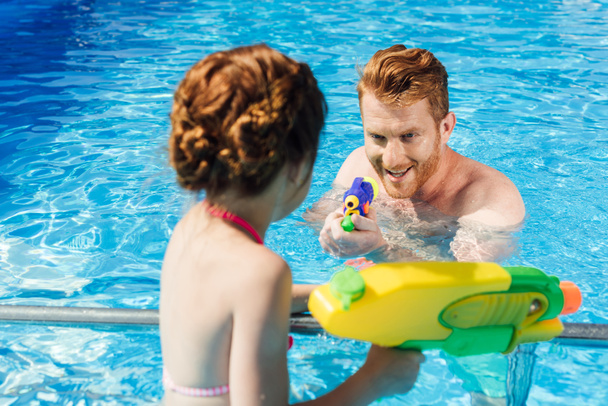 young father and daughter playing with water guns in swimming pool - Foto, Imagem