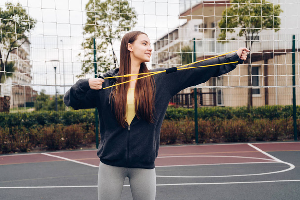 beautiful long-haired girl doing exercises on an outdoor sports field, leading an active lifestyle - Foto, Imagem