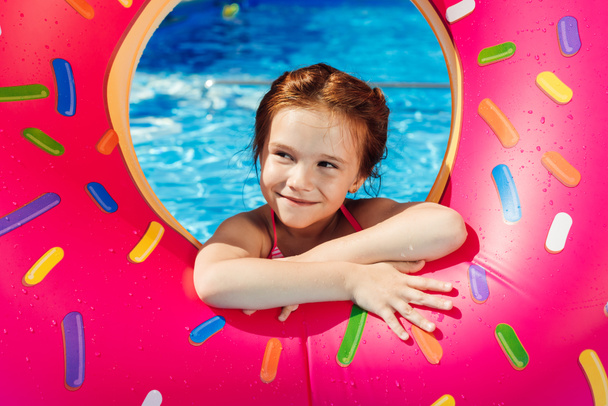 adorable little child with inflatable ring in shape of donut in swimming pool - Photo, Image